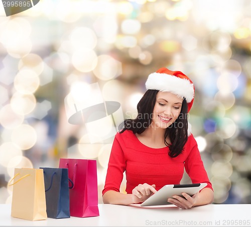 Image of smiling woman with shopping bags and tablet pc