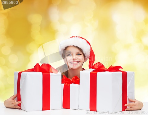 Image of smiling girl in santa helper hat with gift boxes