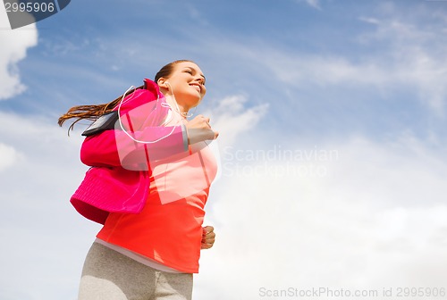 Image of smiling young woman running outdoors