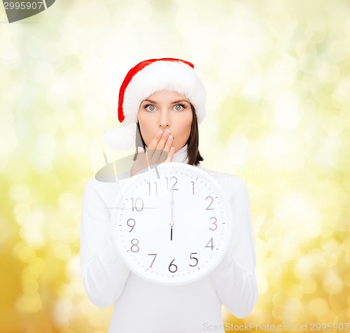 Image of woman in santa helper hat with clock showing 12