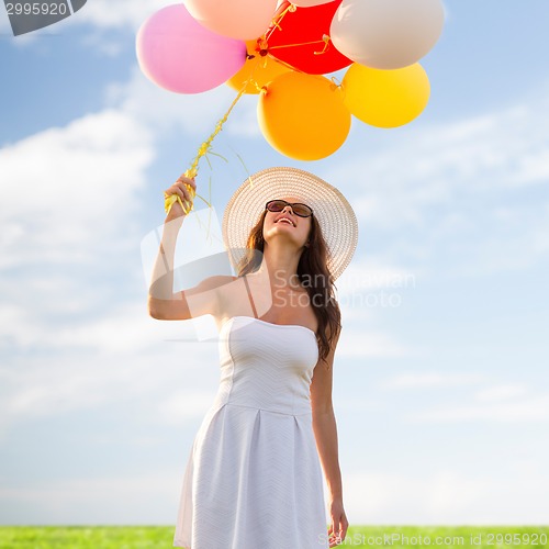 Image of smiling young woman in sunglasses with balloons