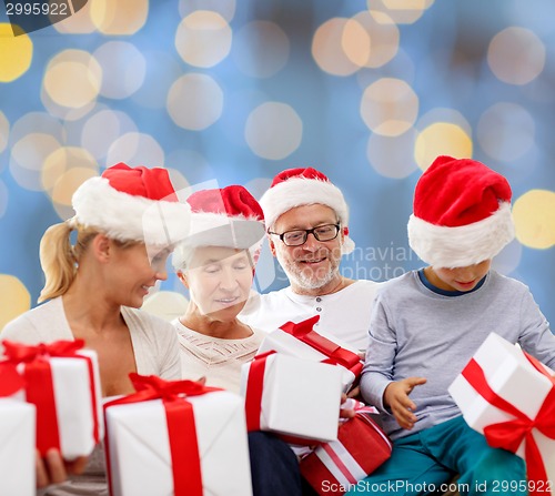 Image of happy family in santa helper hats with gift boxes