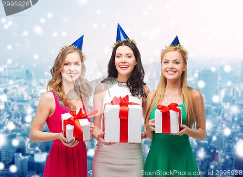 Image of smiling women in party caps with gift boxes