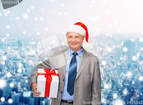 Image of smiling man in suit and santa helper hat with gift