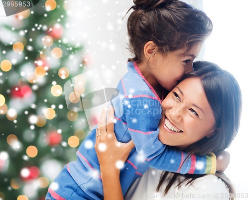 Image of smiling little girl and mother hugging indoors