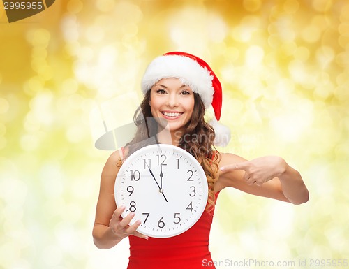 Image of smiling woman in santa helper hat with clock