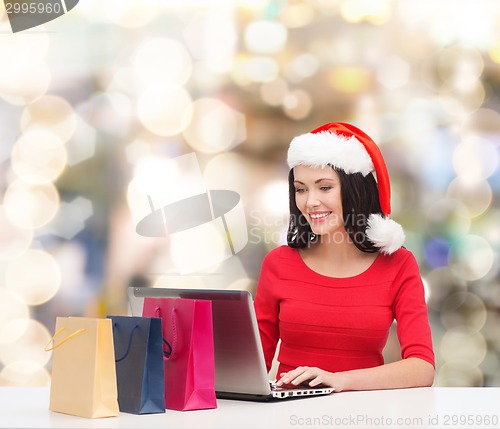 Image of smiling woman in santa hat with bags and laptop