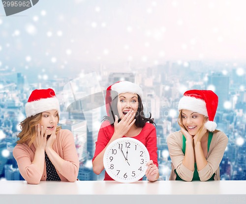 Image of smiling women in santa helper hats with clock