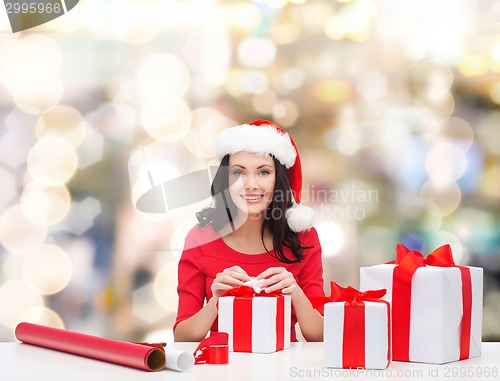 Image of smiling woman in santa helper hats packing gifts