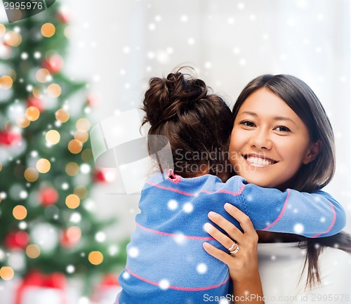 Image of smiling little girl and mother hugging indoors
