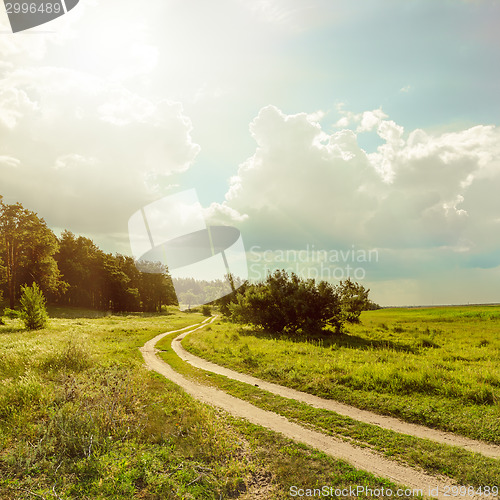 Image of road near forest under sun with low clouds