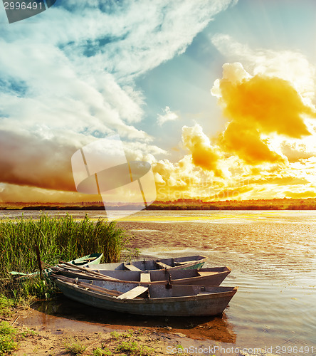 Image of colored sunset over river with boats