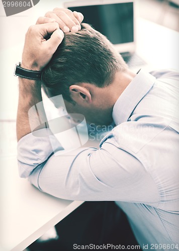 Image of stressed businessman with papers at work