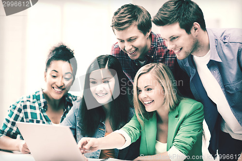 Image of smiling students looking at laptop at school