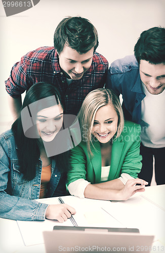 Image of smiling students looking at laptop at school