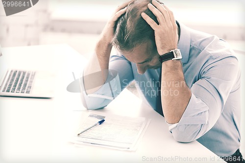 Image of stressed businessman with papers at work