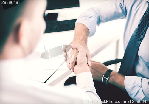 Image of businessmen shaking hands in office