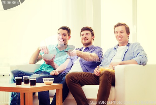 Image of smiling friends with remote control at home