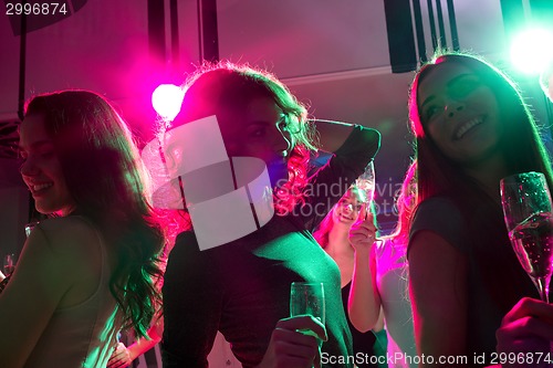 Image of smiling friends with glasses of champagne in club