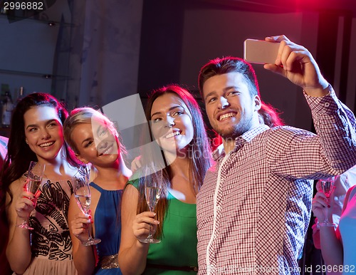 Image of friends with glasses and smartphone in club