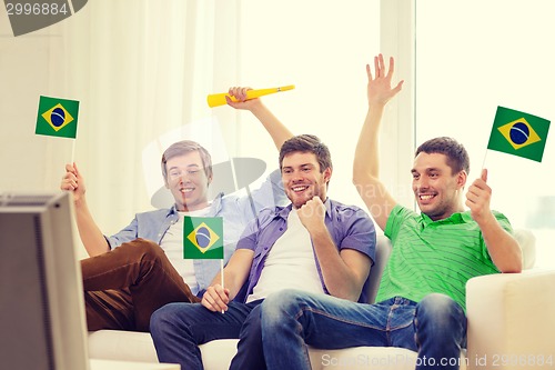 Image of happy male friends with flags and vuvuzela