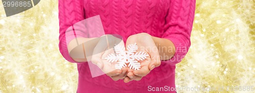 Image of close up of woman in sweater holding snowflake