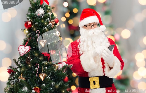Image of santa claus with smartphone and christmas tree