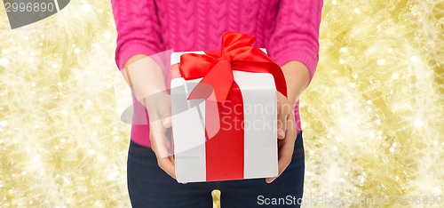 Image of close up of woman in pink sweater holding gift box