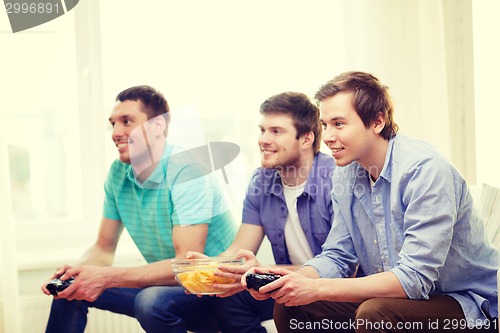 Image of smiling friends playing video games at home