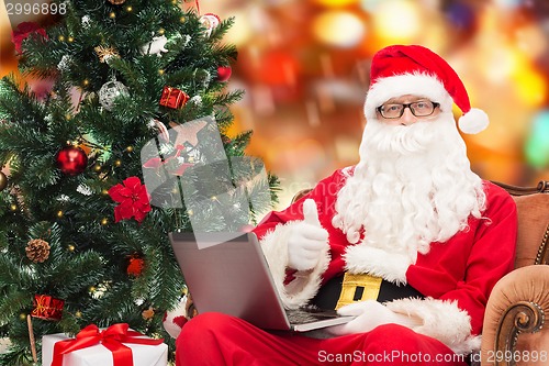 Image of man in costume of santa claus with laptop