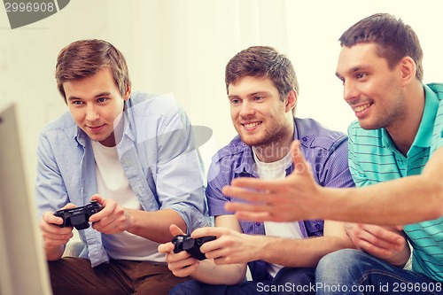 Image of smiling friends playing video games at home