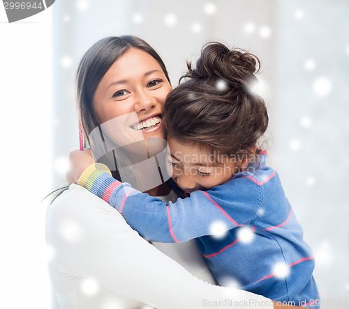 Image of smiling little girl and mother hugging indoors