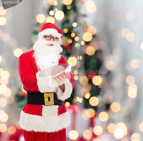 Image of man in costume of santa claus with notepad