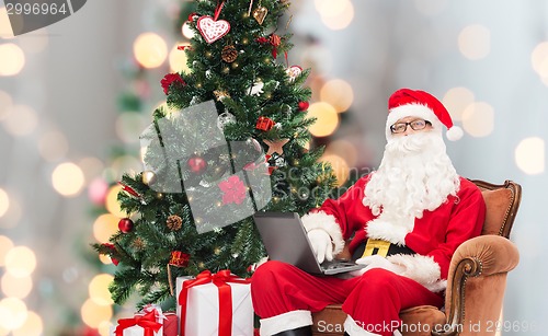 Image of man in costume of santa claus with laptop