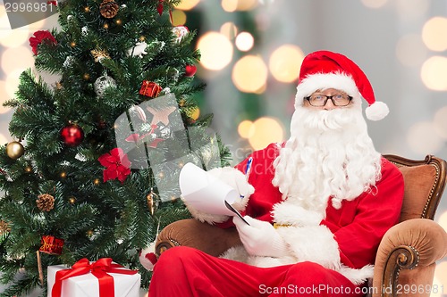 Image of man in costume of santa claus with notepad