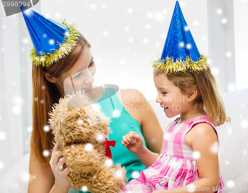 Image of mother and daughter in party hats with toy