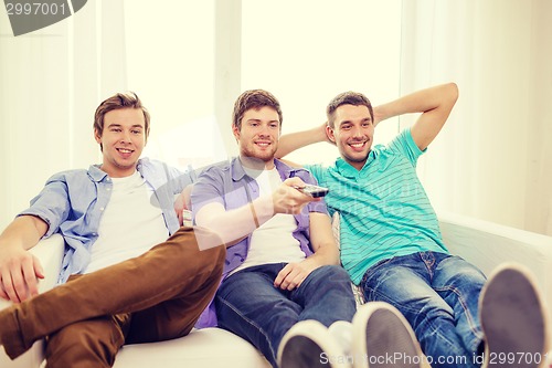 Image of smiling friends with remote control at home