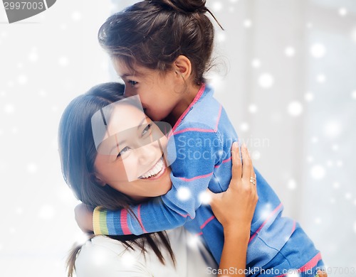 Image of smiling little girl and mother hugging indoors