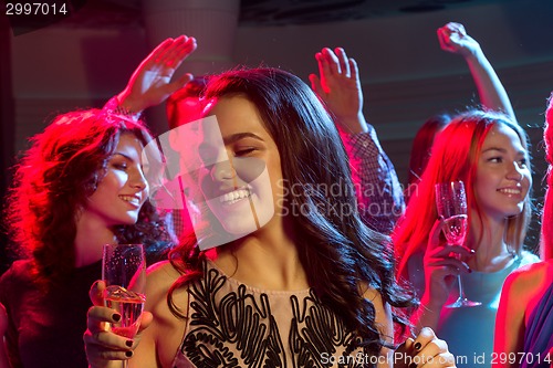 Image of smiling friends with glasses of champagne in club