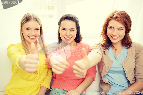 Image of three girlfriends showing thumbs up at home
