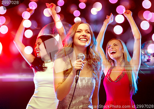 Image of three smiling women dancing and singing karaoke