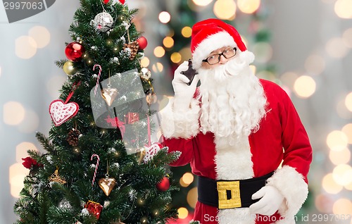 Image of santa claus with smartphone and christmas tree