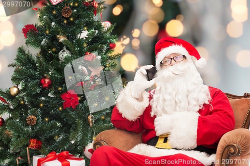 Image of santa claus with smartphone and christmas tree