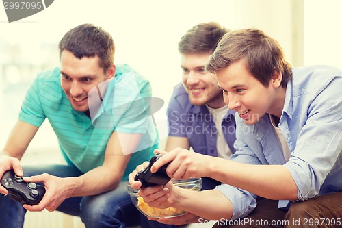 Image of smiling friends playing video games at home