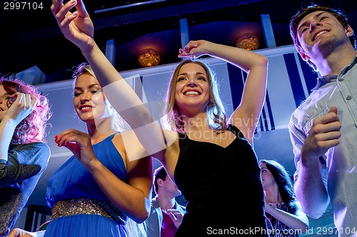 Image of smiling friends dancing in club