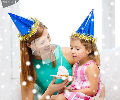 Image of mother and daughter in party hats with cake