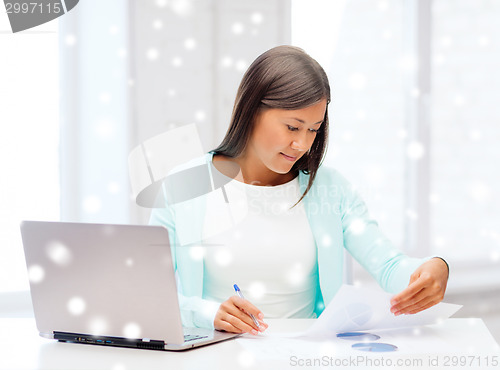 Image of smiling young woman with laptop and papers