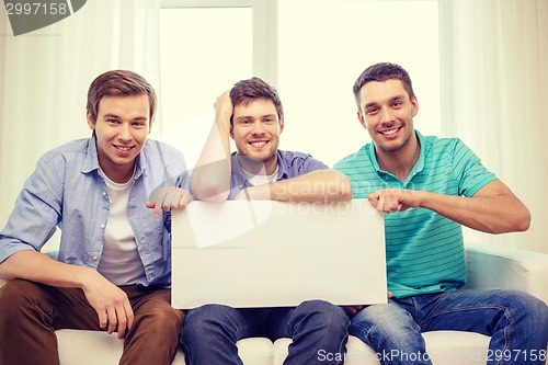 Image of smiling male friends holding white blank board