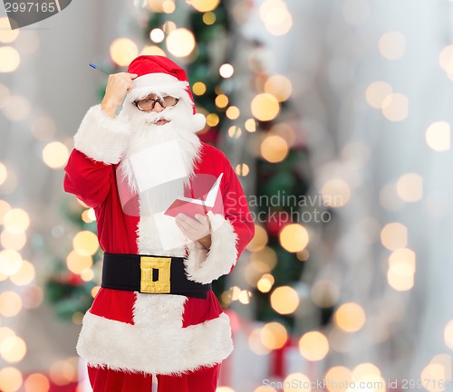 Image of man in costume of santa claus with notepad