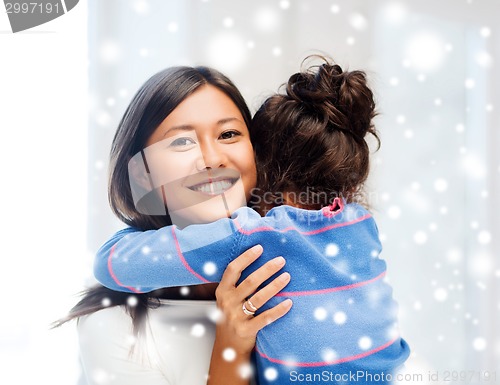 Image of smiling little girl and mother hugging indoors